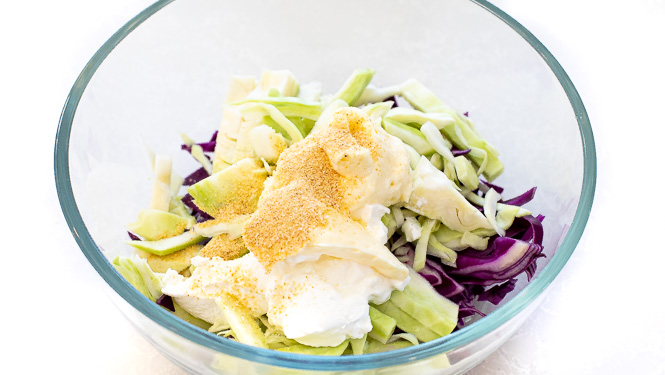 Coleslaw ingredients in a glass mixing bowl. 