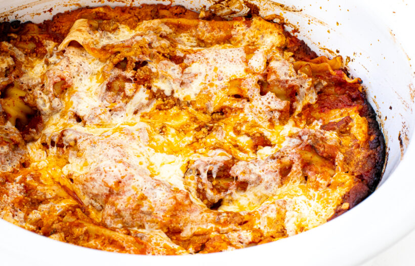 Baked lasagna in a white slow cooker liner.