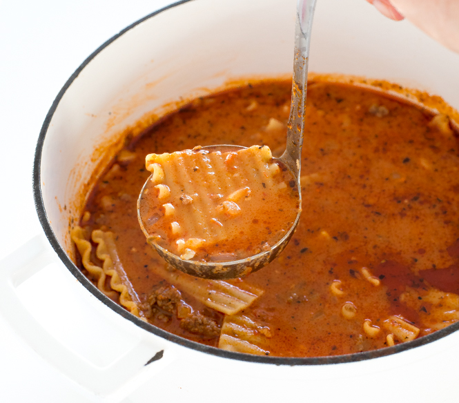 close up shot of ladle scooping noodle and broth out of soup bowl