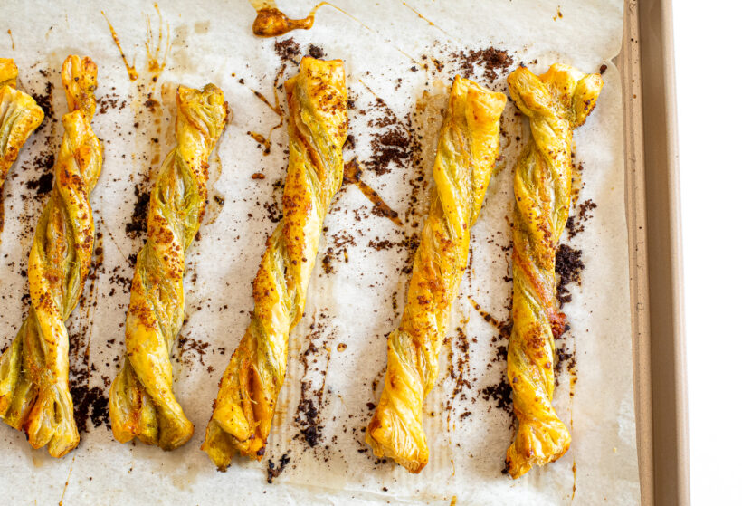 Pesto parmesan cheese straws on a baking sheet after being baked. 