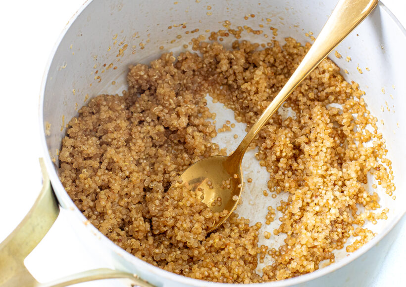Cooked quinoa in a pot with a spoon.