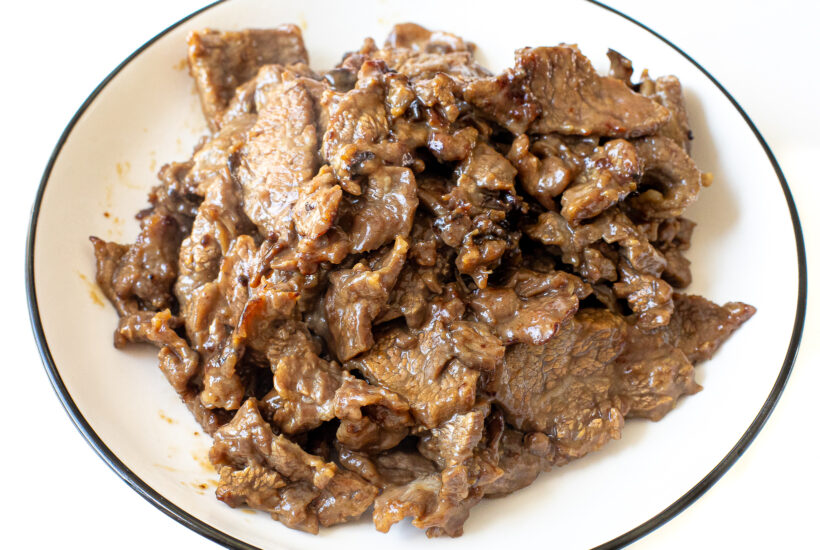 cooked flank steak on a white plate