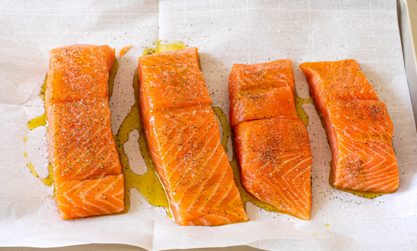 Raw salmon on a baking sheet lined with parchment paper. 