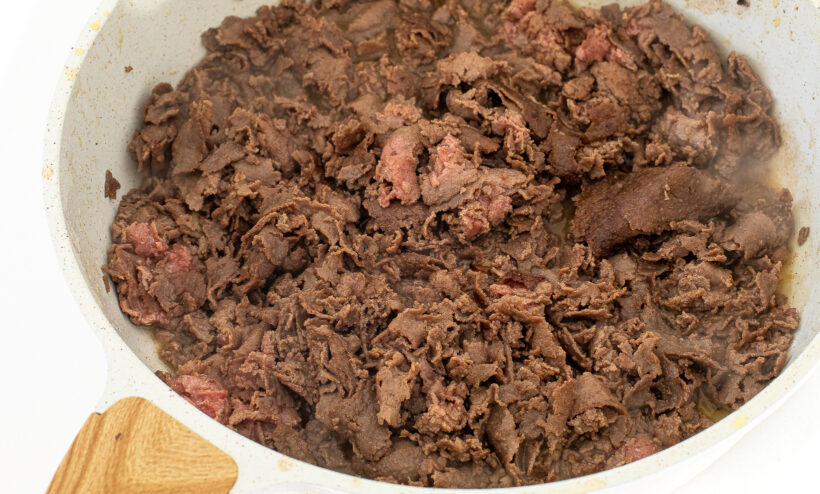 Sliced beef in a frying pan.