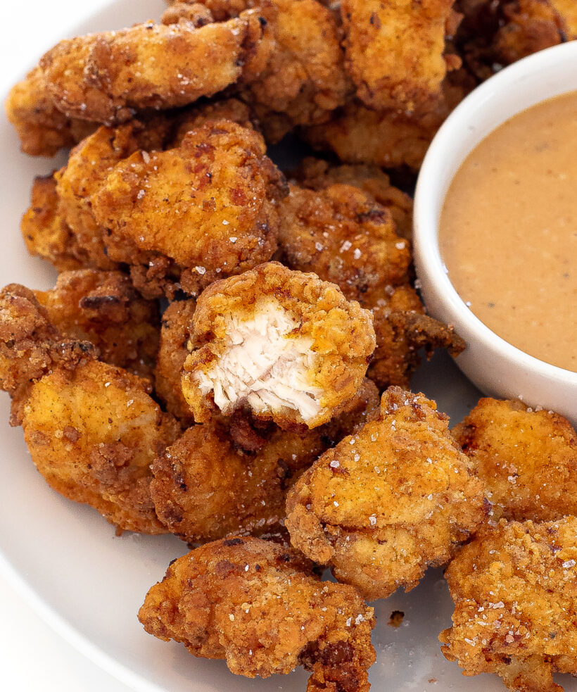 Chick fil a nuggets on a serving plate with a side of sauce next to them.