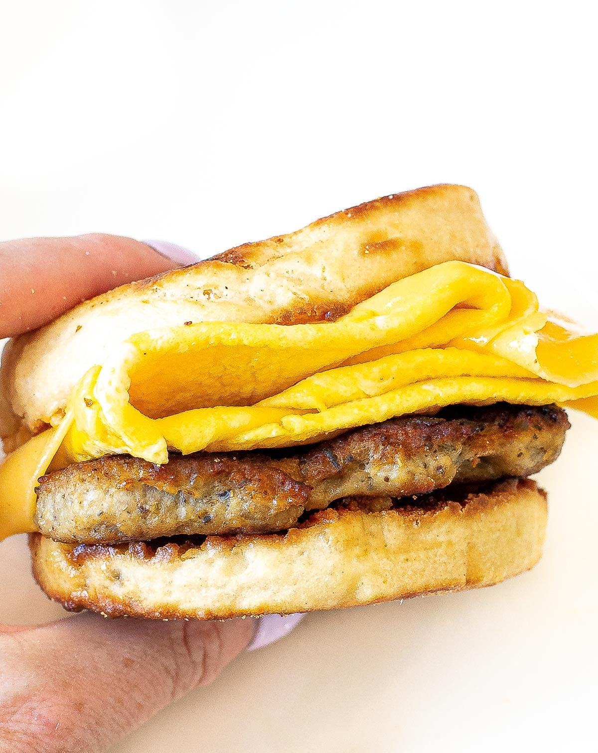 author holding egg mc muffin with cheese, egg and homemade chicken breakfast sausage