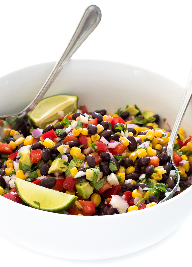 A spoon and a fork sitting in the Black Bean Corn Salsa in a white bowl.