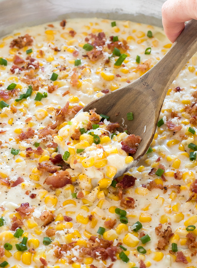 homemade creamed corn in large skillet topped with bacon and chives