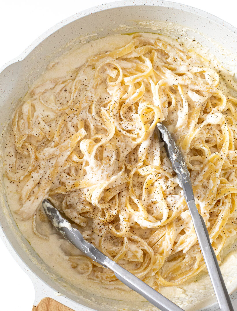 Cottage Cheese Alfredo in a white skillet with tongs.
