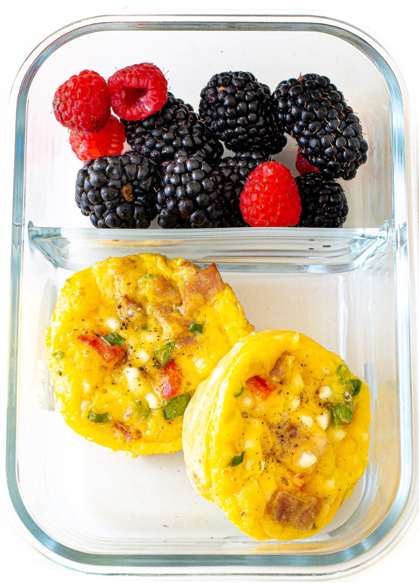 Egg cups and fresh berries in a glass container.