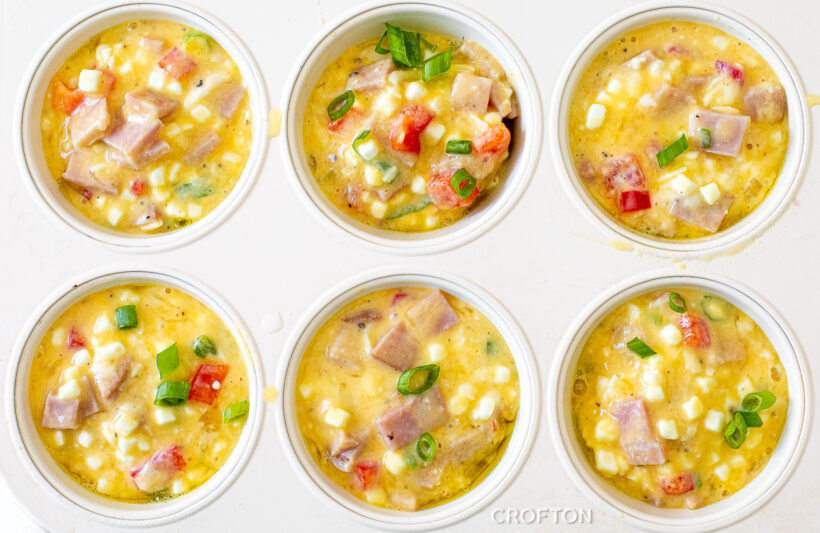 Unbaked egg cups in a muffin tin.