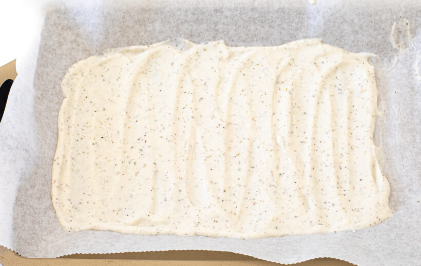 Cottage cheese mixture spread onto a baking sheet lined with parchment paper.