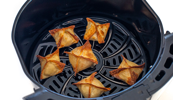 Air fryer crab rangoon after being cooked in the air fryer, still in the air fryer basket. 