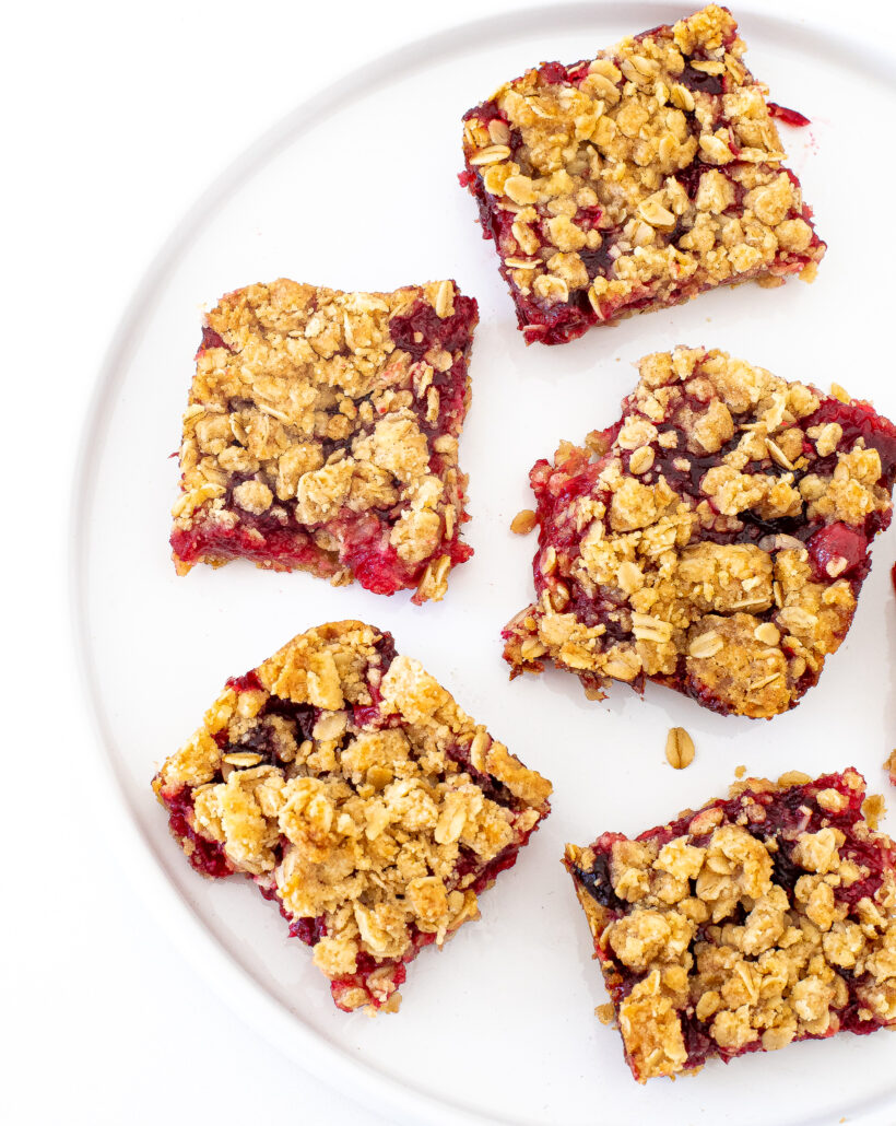 A top down view of cranberry crumb bars laid on a white plate.