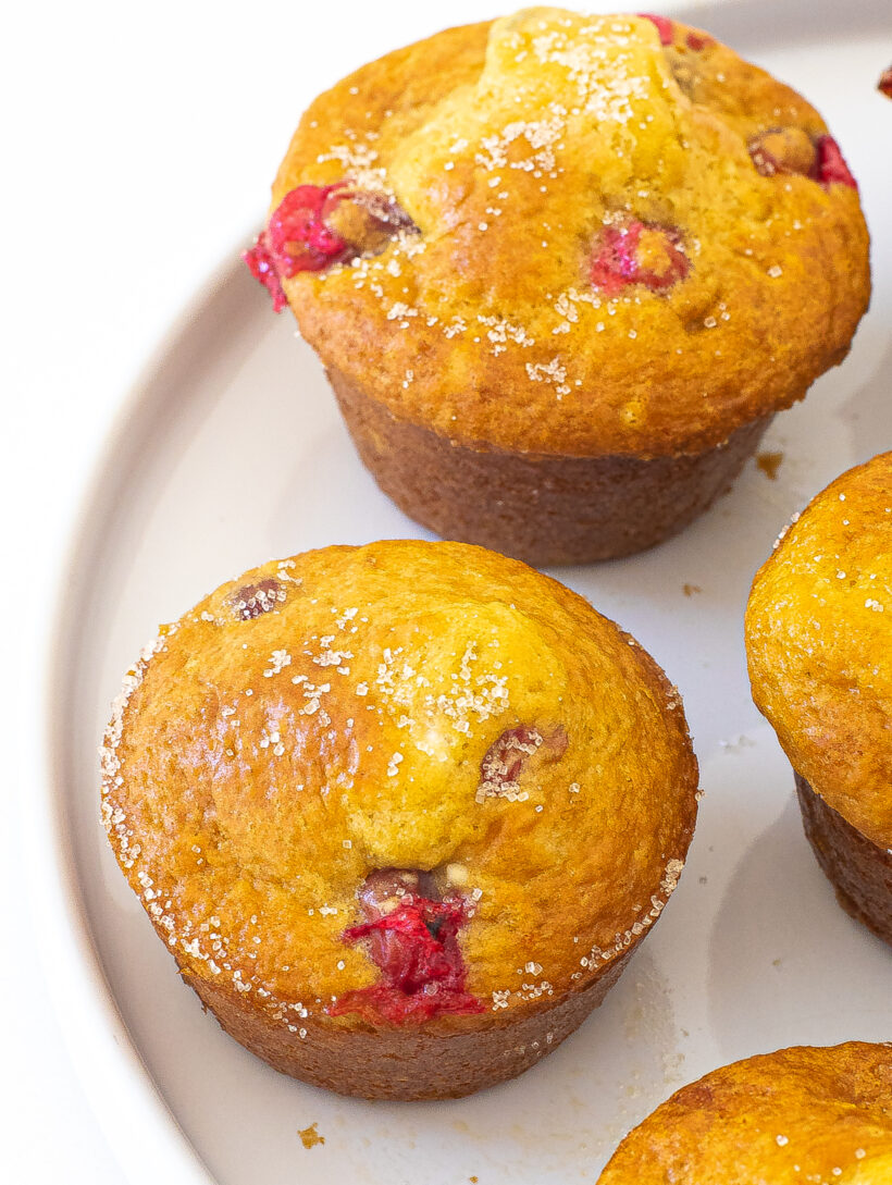Close up of cranberry orange muffins on a white plate.