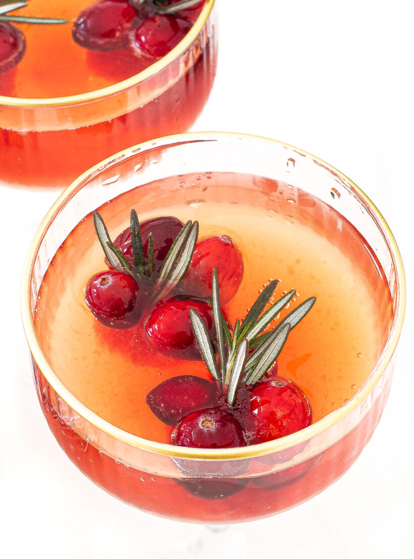 overhead shot of cranberry pomegranate punch in clear glass with gold rim
