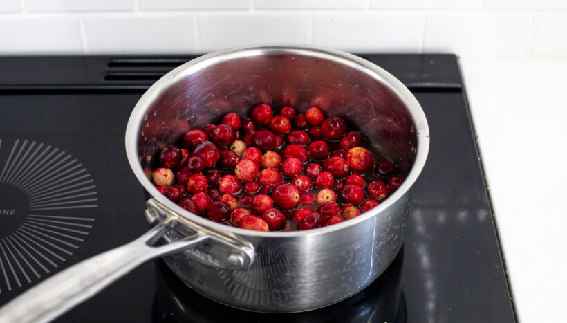simmering cranberries, water, sugar and orange juice on stove