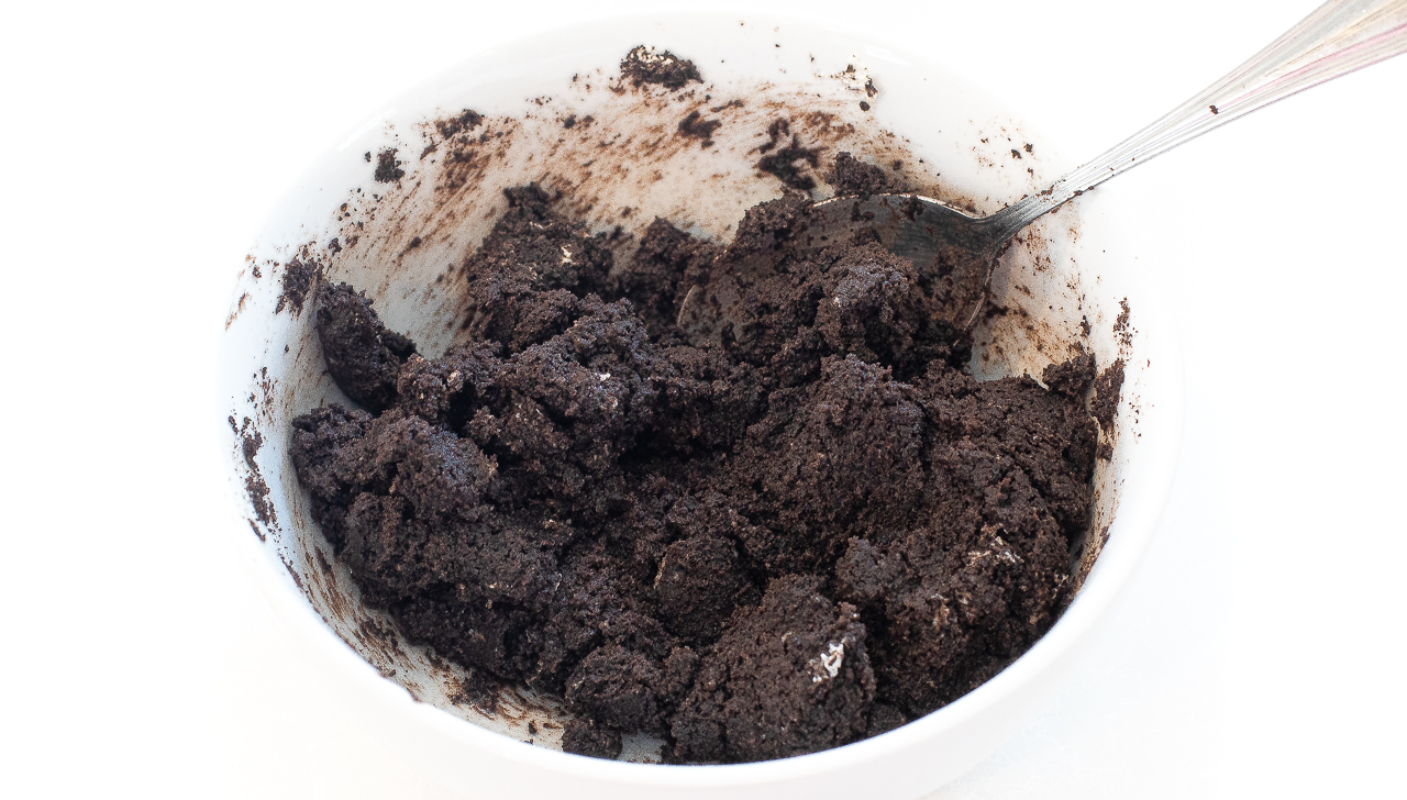 cream cheese and cookie crumbs mixed together in white bowl with spoon