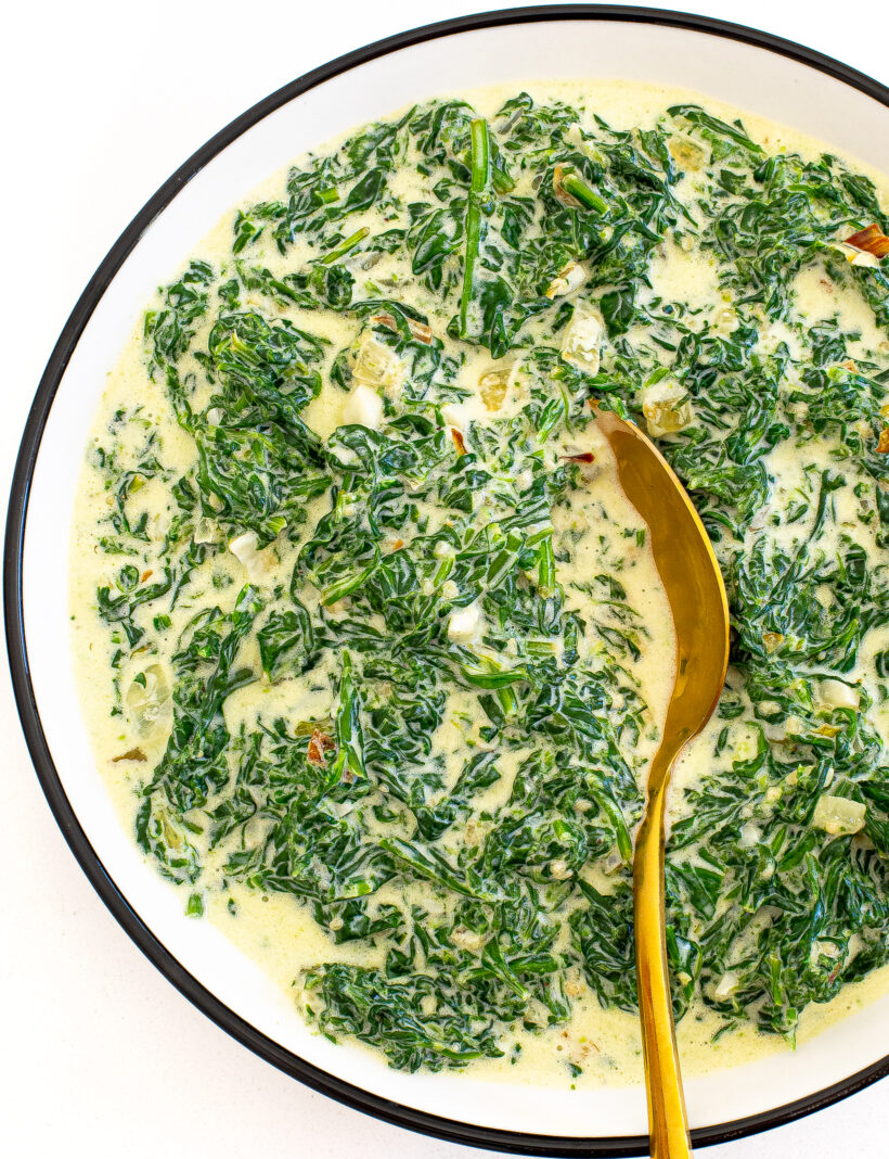 creamed spinach in a skillet with a serving spoon.