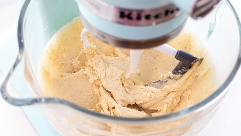 Butter and sugar being mixed in the bowl of a stand mixer.