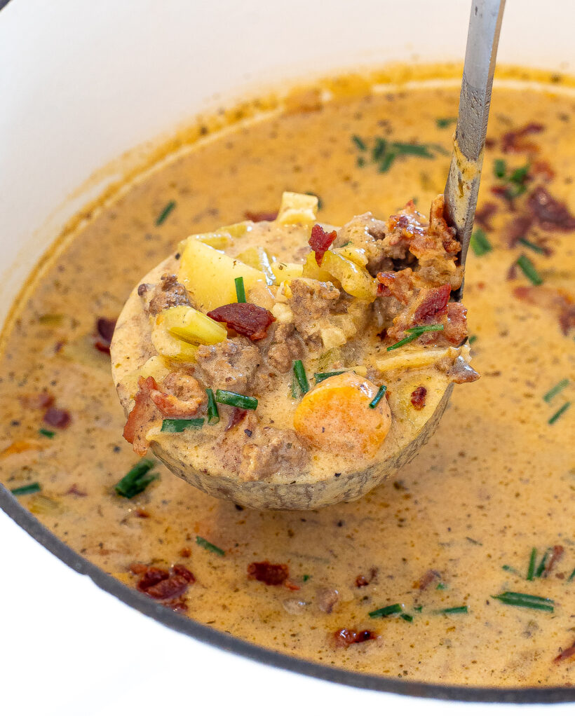 Cheeseburger soup with a ladle scooping out a serving.