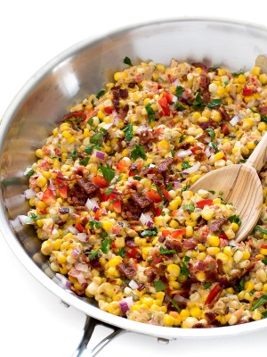 Homemade Confetti Corn with onion, peppers, and bacon in a skillet with a wooden serving spoon | chefsavvy.com