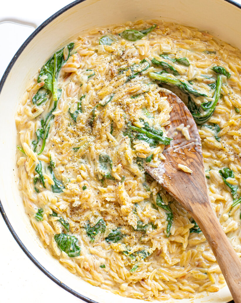 Creamy boursin orzo in a skillet with a wooden spoon.