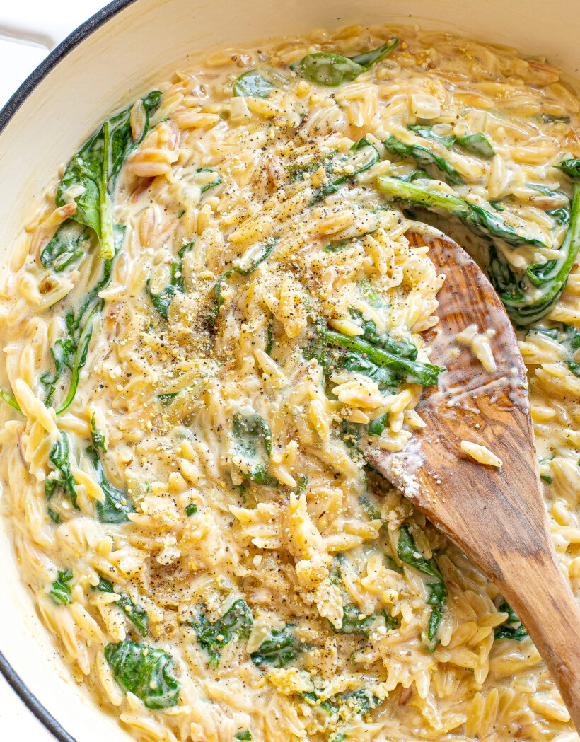 Creamy boursin orzo in a skillet with a wooden spoon.