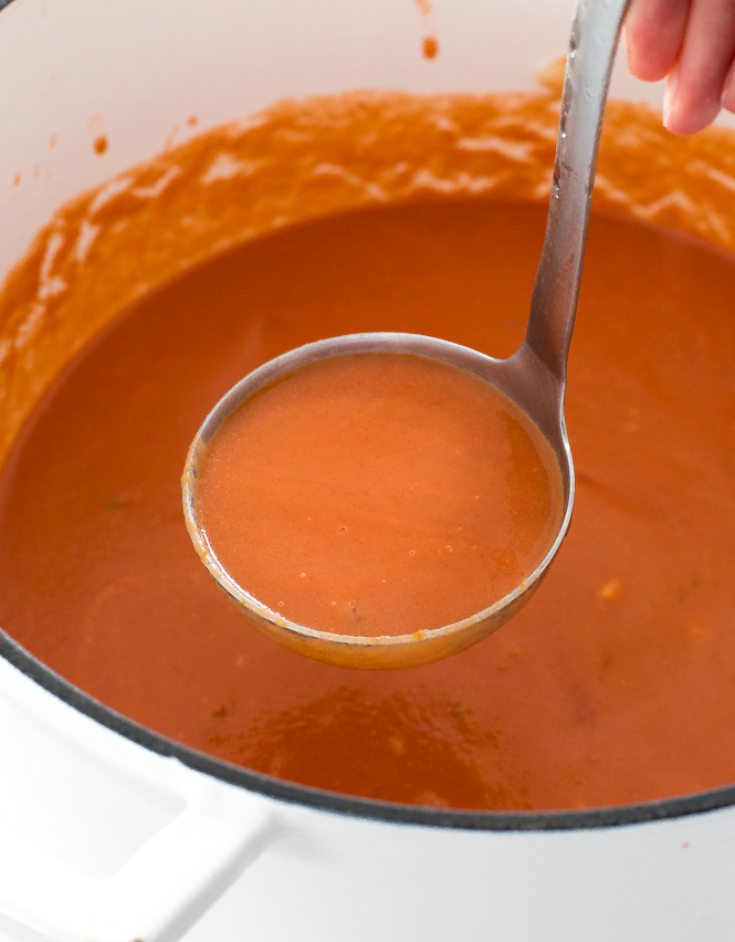 Tomato Soup in white cast iron pot with a ladle