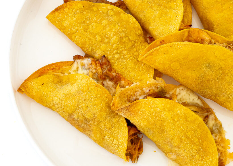 Crispy Baked Chicken Tacos placed on a white plate.