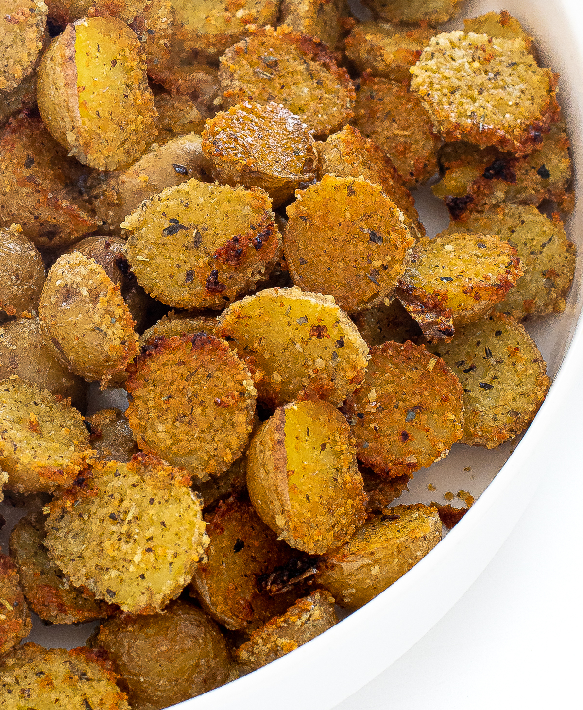 Parmesan crusted potatoes in a white serving bowl. 