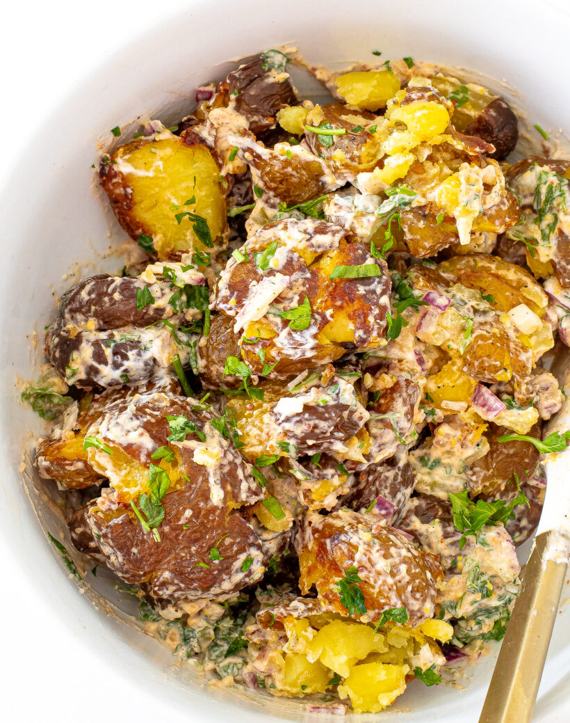 A close up view of Crispy Roasted Potato Salad in a white mixing bowl.