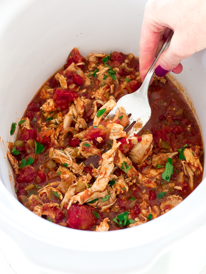 Slow Cooker Mexican Chicken in a crockpot with a hand digging in with a silver fork.