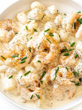 Creamy gorgonzola gnocchi and shrimp serve in a white bowl.