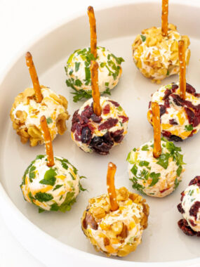 Mini Cheese Balls with pretzels on a white plate.