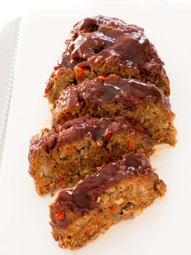 overhead shot of sliced meatloaf on white tray with serrated knife