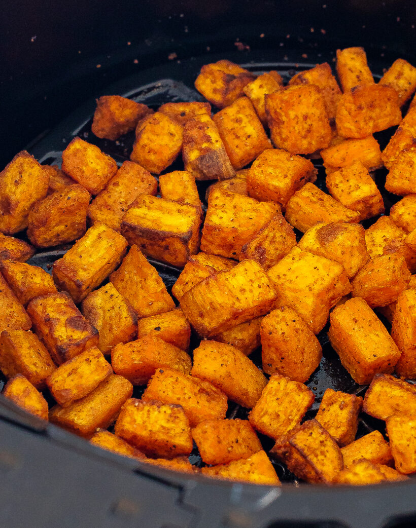 Roasted cubes of sweet potato in an air fryer basket. 