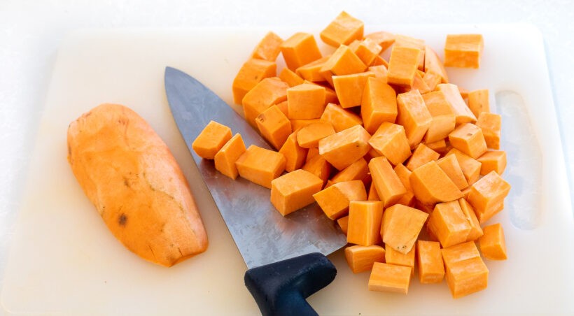 Sweet potatoes chopped on a cutting board.