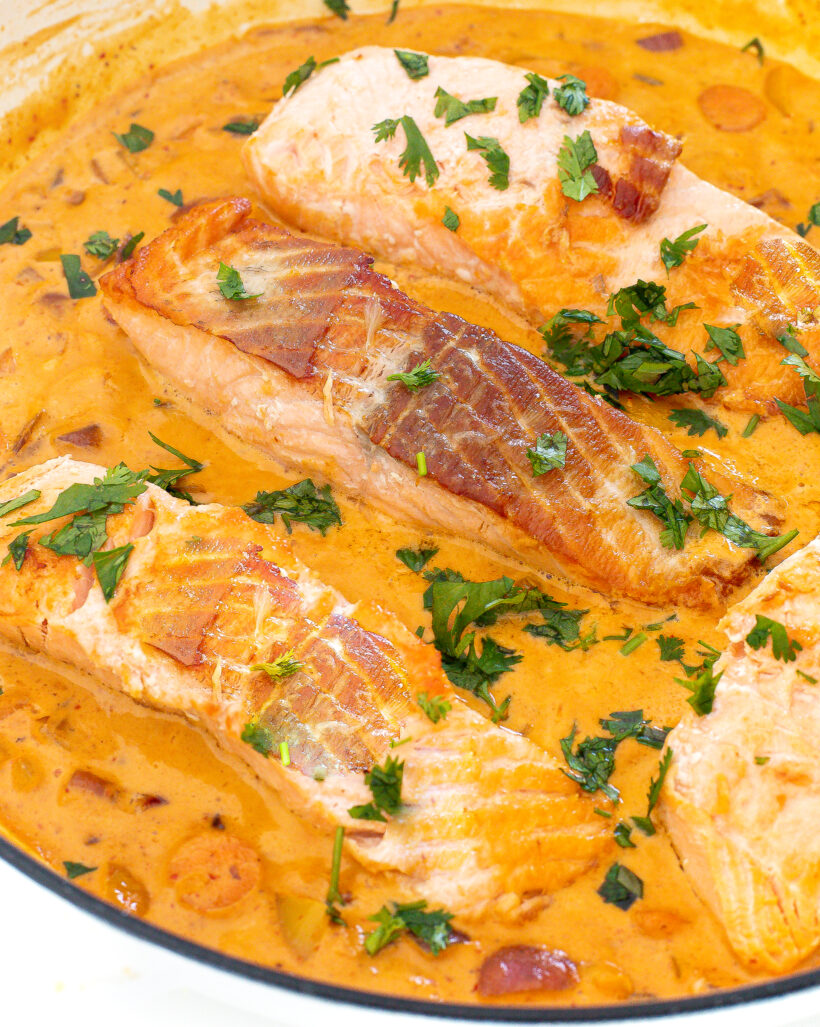 Salmon fillets in a curry sauce in a sauté pan.