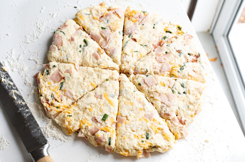 Ham and cheese scone dough in a disc on a floured surface and cut into triangles. 