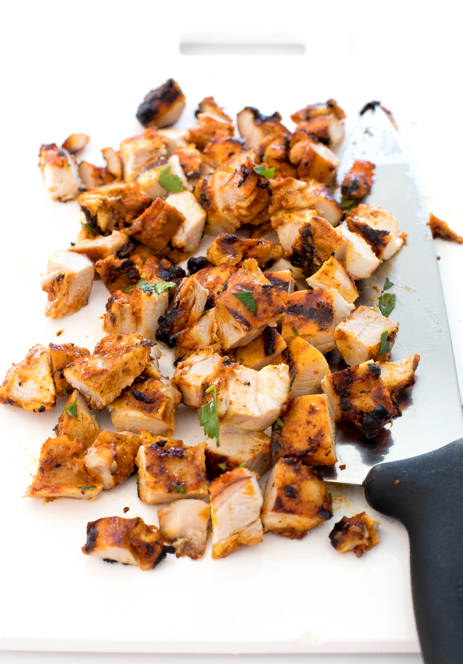 Sliced pollo asado on a white chopping board with a knife