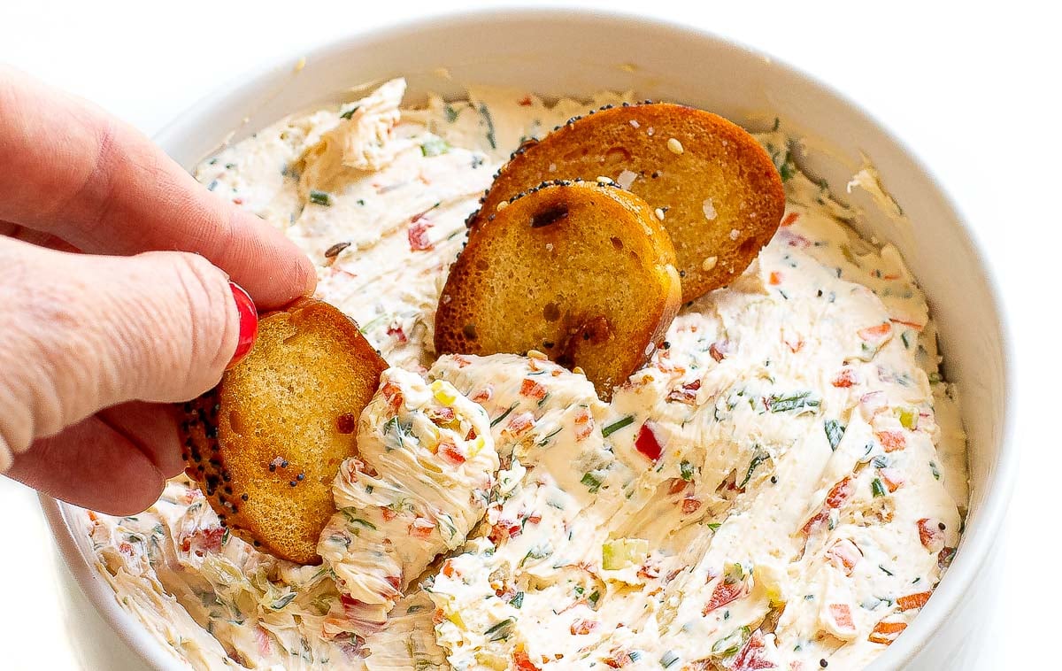 dipping bagel chips into veggie cream cheese