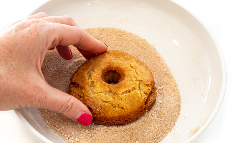 dipping fried donuts in cinnamon sugar mixture