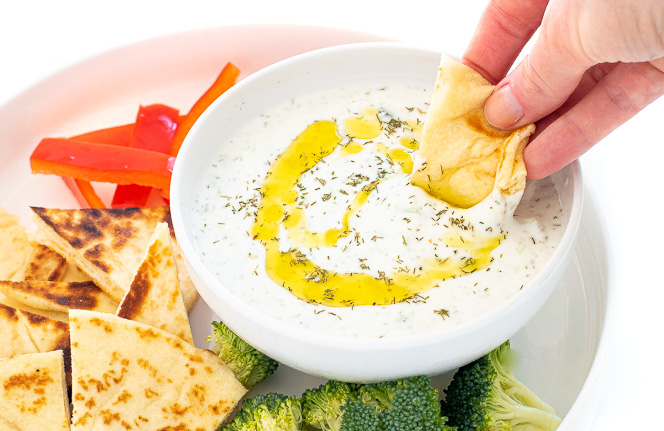 Dipping a piece of pita into the tzatziki sauce.