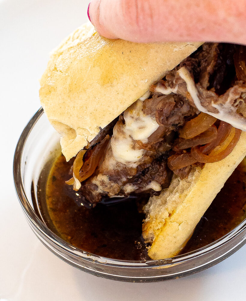 dipping French dip sandwich in au jus