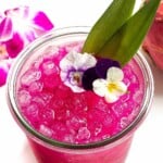 Dragon fruit margarita garnished with flowers.
