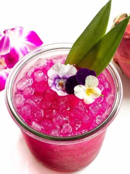 Dragon fruit margarita garnished with flowers.