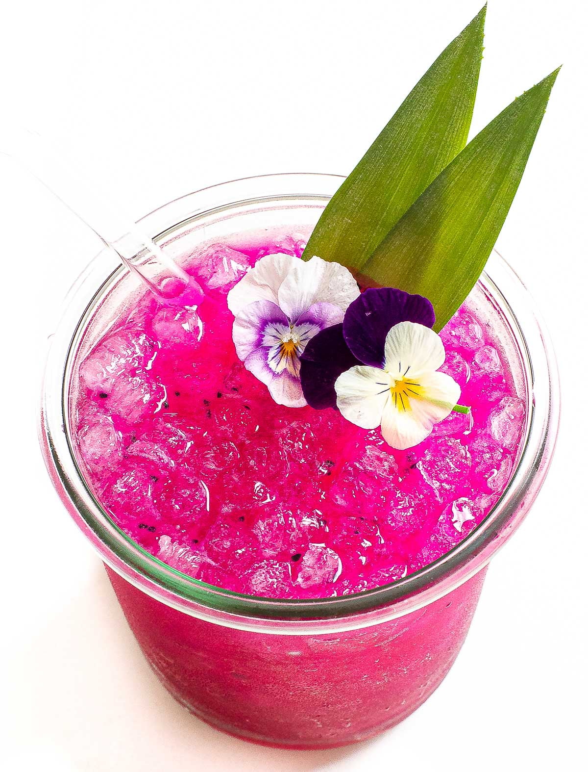 Dragon fruit margarita in a glass with ice and a straw.