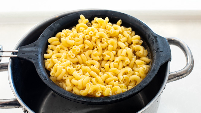 Macaroni pasta being drained after being cooked.