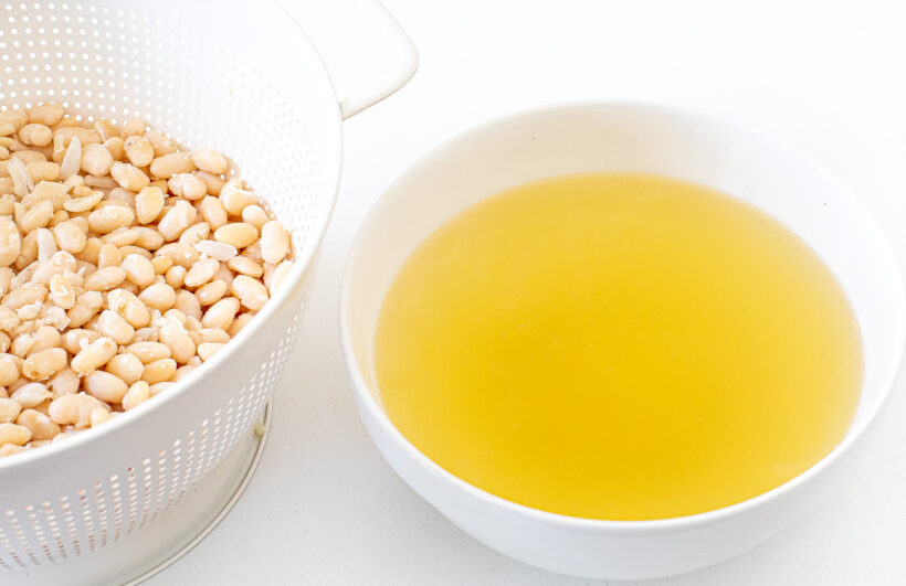 Beans in a colander with the cooking liquid reserved in a large bowl.